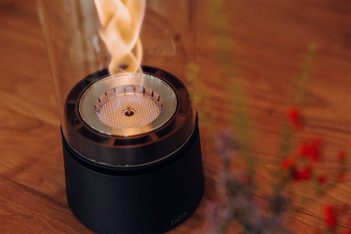 SPIN air 900 Tischfeuer mattschwarz SPIN air 1200 und 900 mattschwarz auf einem Küchentisch mit vier Personen welche mit einem Rotwein anstoßen close-up