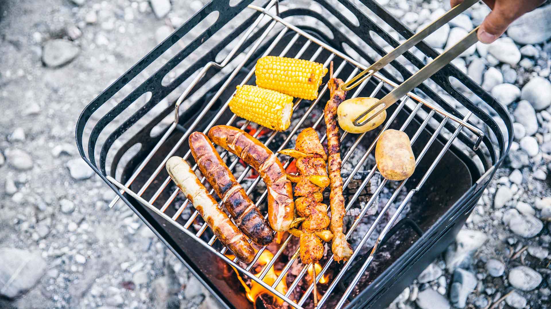 Une scène accueillante avec une personne qui cuisine du poulet sur un gril, mise en valeur par la présence du set de barbecue CUBE.