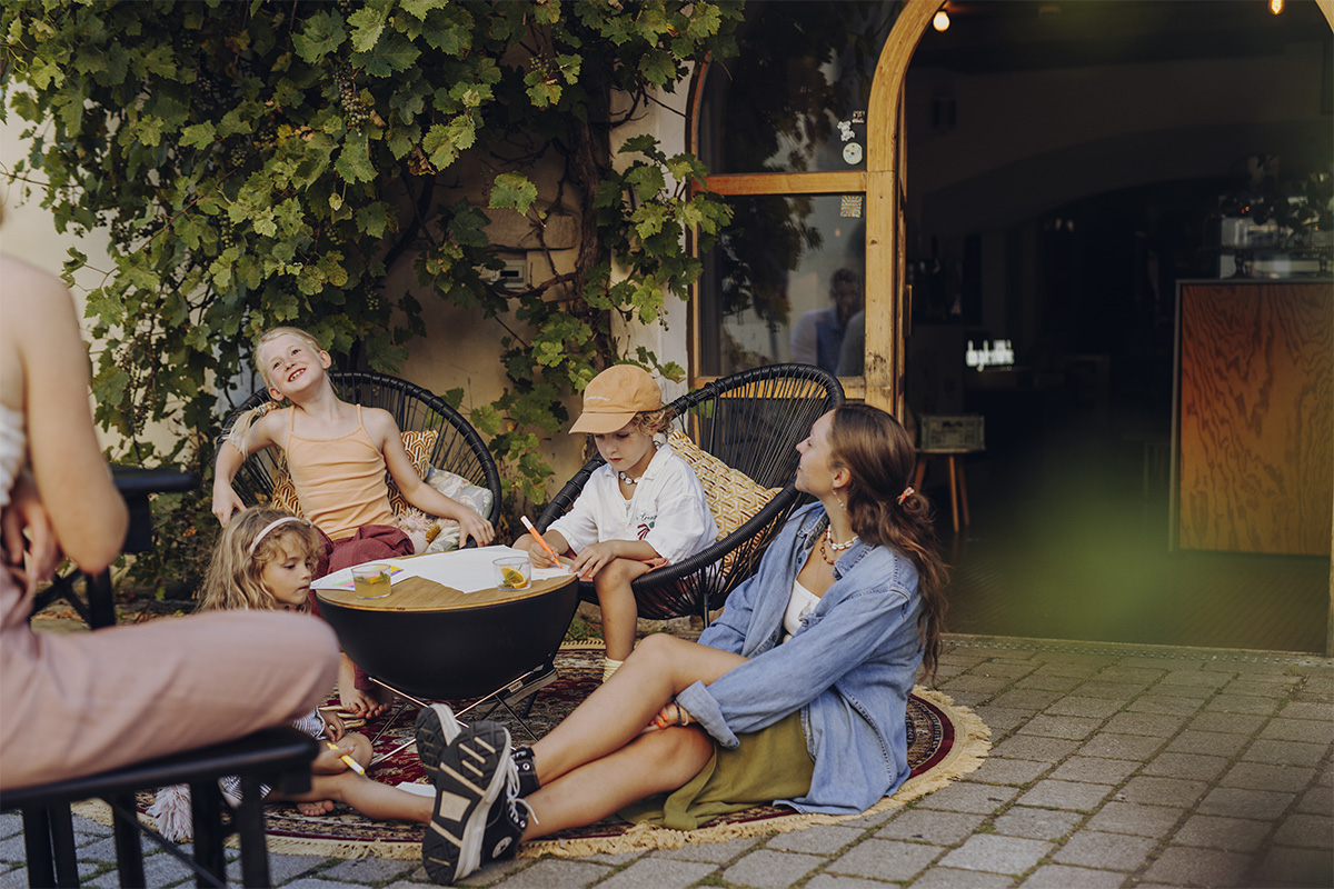 BOWL 57 Auflagebrett Das 00569 BOWL 57 Brett fügt sich nahtlos in die Umgebung ein, in der eine Gruppe von Menschen auf einer Terrasse sitzt.