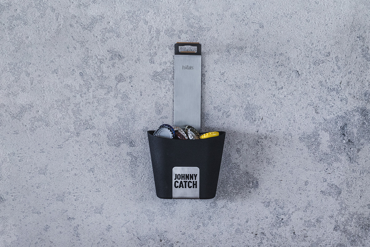 Cette image montre un sac noir avec une étiquette jaune accrochée, avec la tasse JOHNNY CATCH.