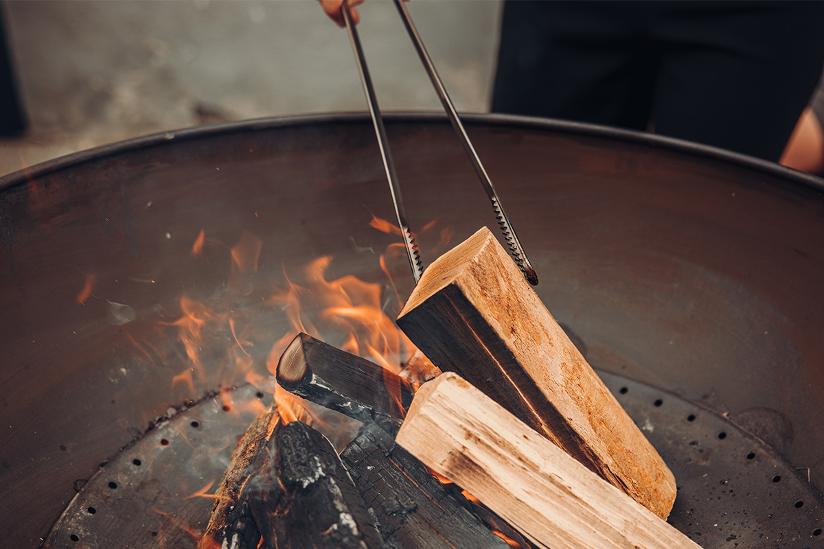 Une vue d'une personne en train de cuisiner quelque chose sur un feu, avec des pinces à feu.
