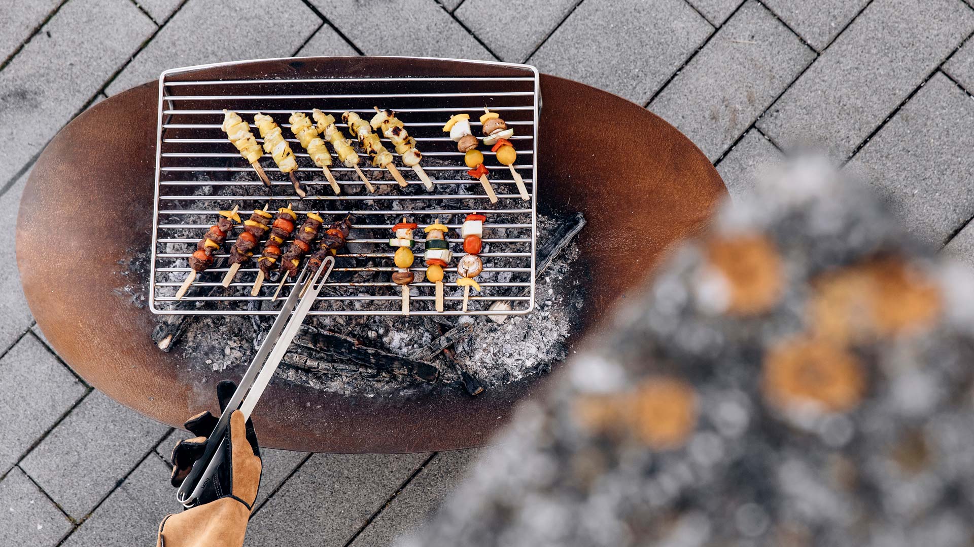 Auf diesem Bild ist eine Person am Grillen, mit dem ELLIPSE Grillrost.