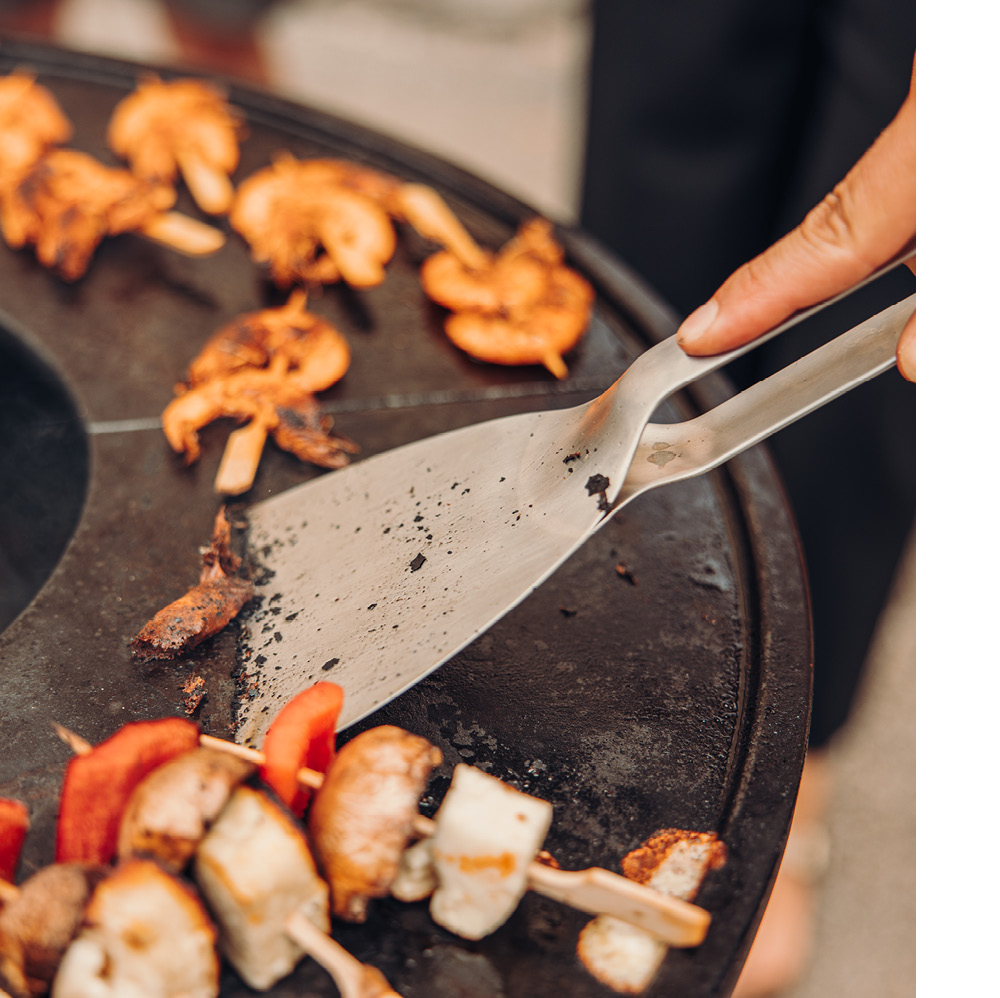 Une personne nettoie la Plancha BOWL avec un grattoir.