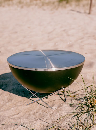 Eine schwarze Bowl steht auf einem sandigen Strand und zeigt den BowlDECKEL.