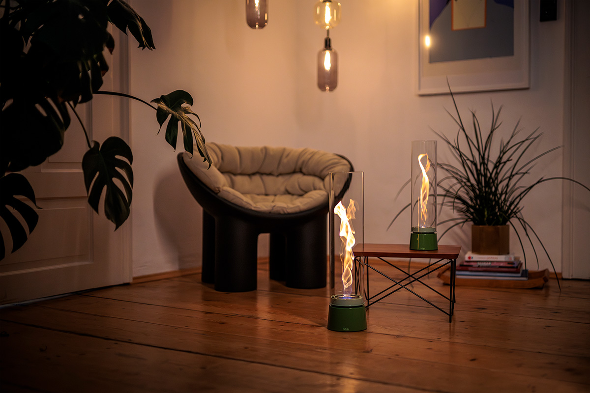 The Spin Air 1200 Tablefire Emaille Green fits naturally into this quiet corner with a wooden chair and leafy plant.