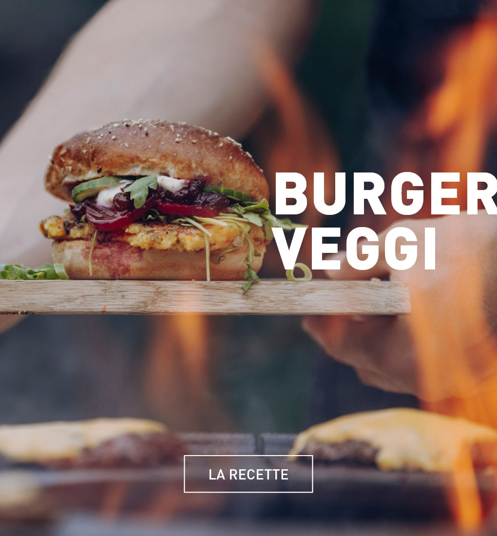 Une personne tenant un hamburger sur un grill.