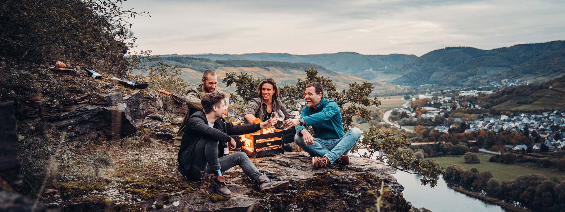 Eine einladende Szene mit zwei Personen, die auf einem Felsbrocken sitzen und ein Lagerfeuer genießen, hervorgehoben durch die Anwesenheit des Crate Fireplace.