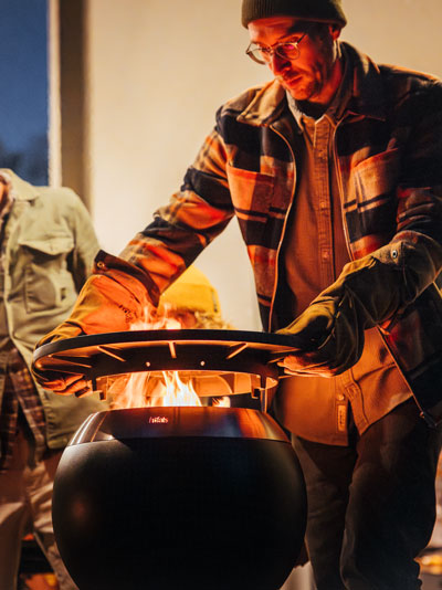 Un homme cuisine sur un grand grill, le MOON 45 Plancha complète le moment avec son design réfléchi.