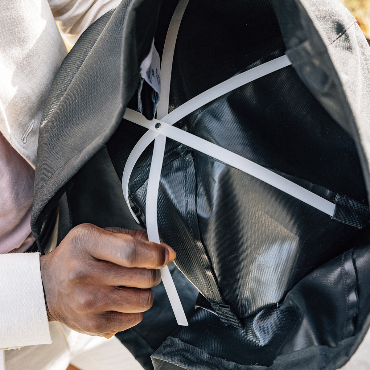 MOON 45 Abdeckhaube Ein Mann hält eine schwarze Abdeckung, zeigt sie von innen mit ihren strukturellen Elementen. Das 00815 Moon 45 Cover.