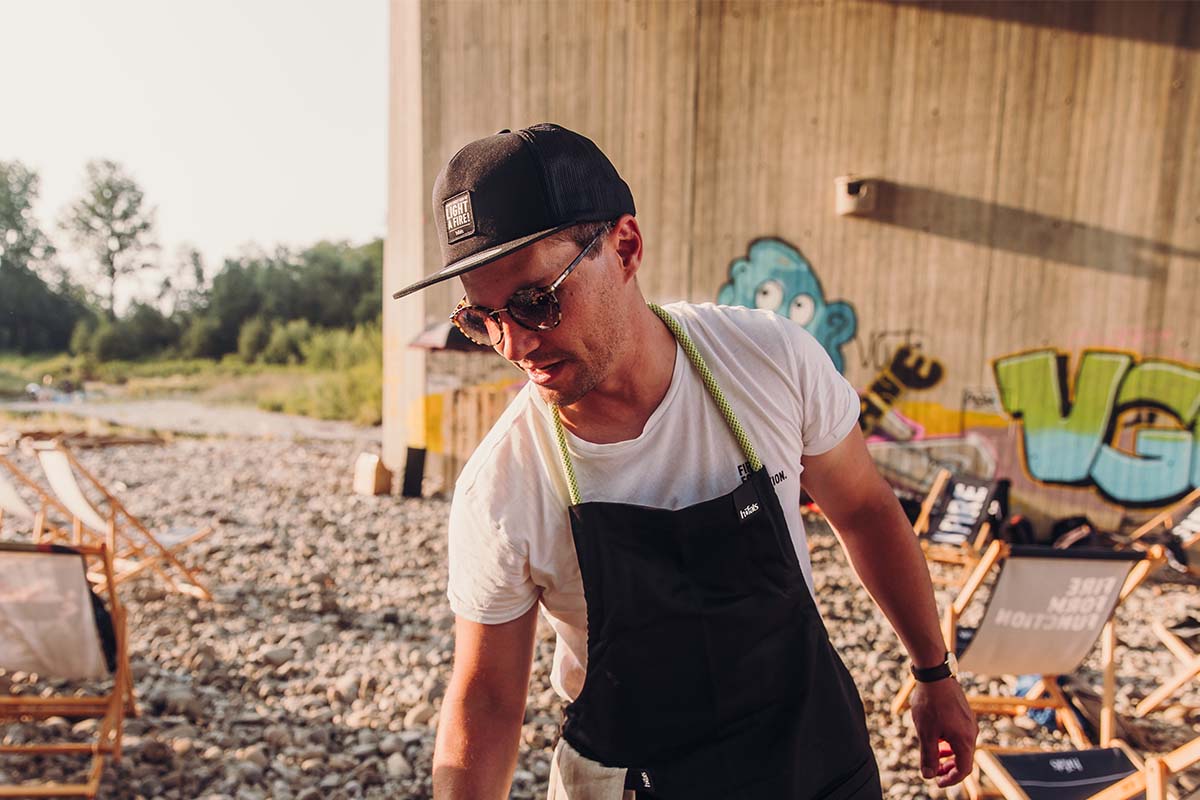 CASQUETTE noir Un homme en tablier et chapeau debout sur la plage.