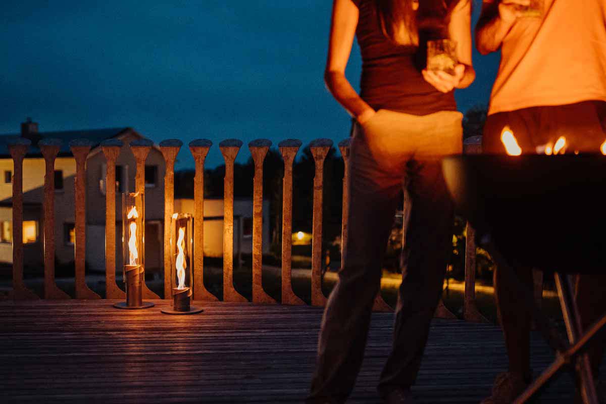 SPIN 1200 Stand Elevation silver Depicted here is a couple sitting on a deck at night, with the SPIN 90 Table Fire silver.